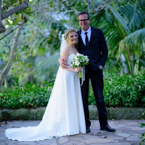 A picture of a man in a suit and a woman in a wedding dress holding a bouquet of flowers.
