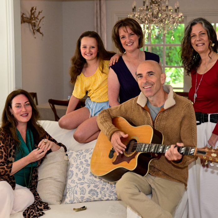 A photograph of a Family on a couch, with a man playing guitar.