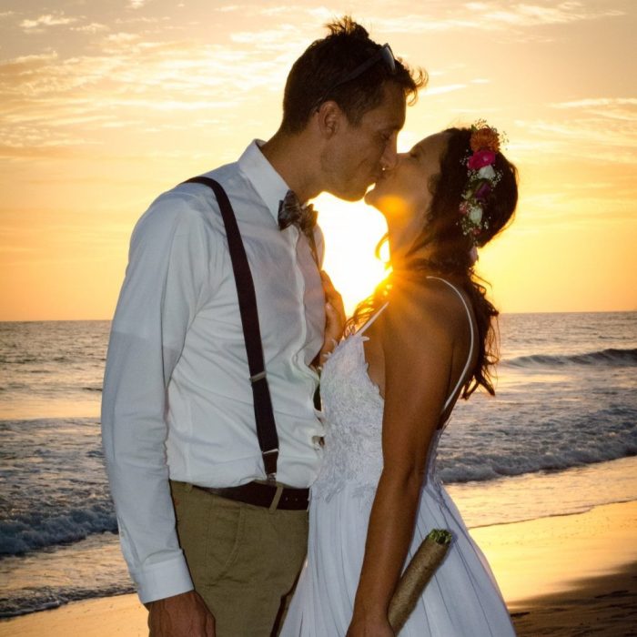 cropped-karina-2-1.jpg A wedding shot of a couple on the beach, with a sunset in the background.